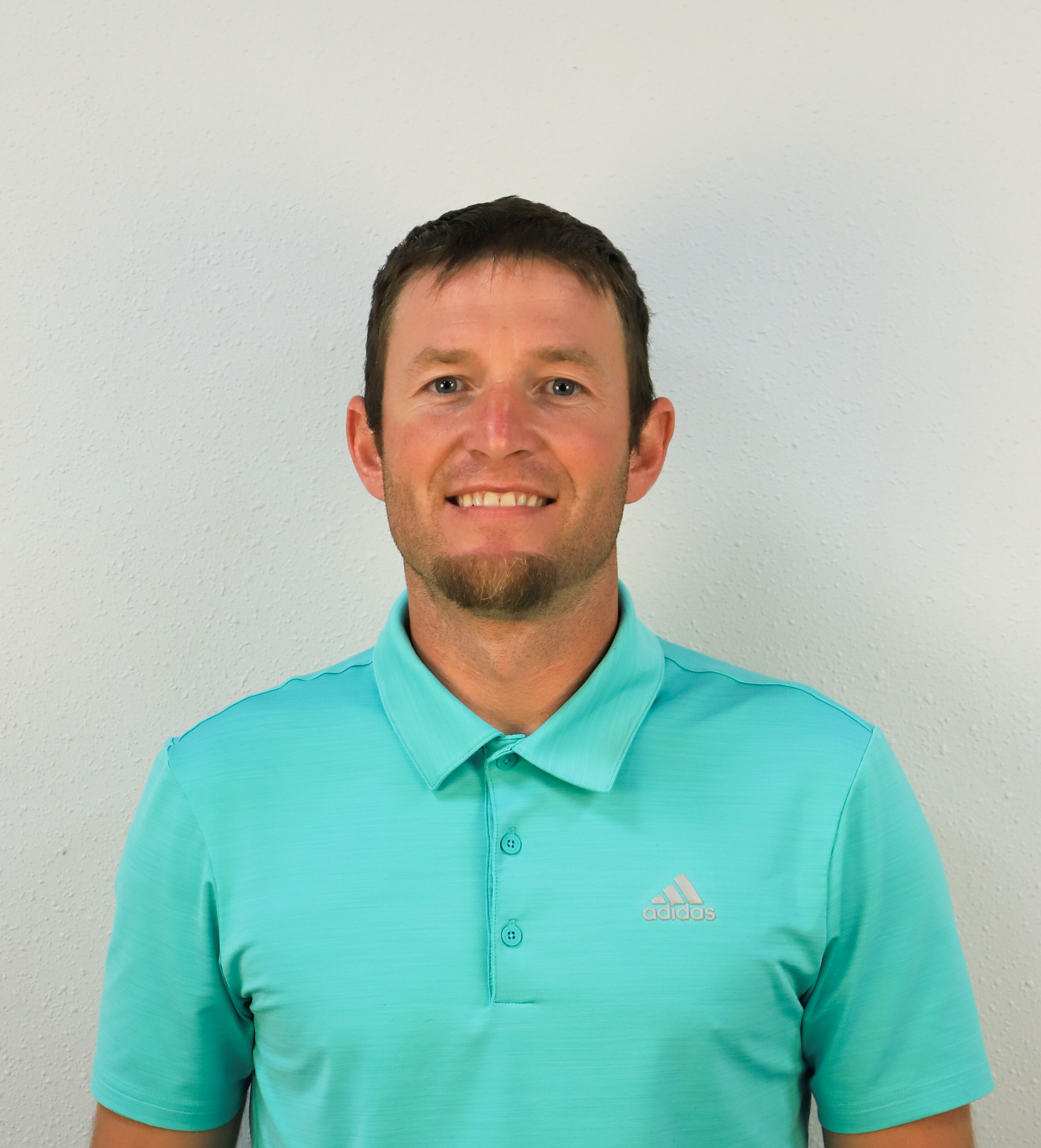 Man wearing a turquoise polo shirt.