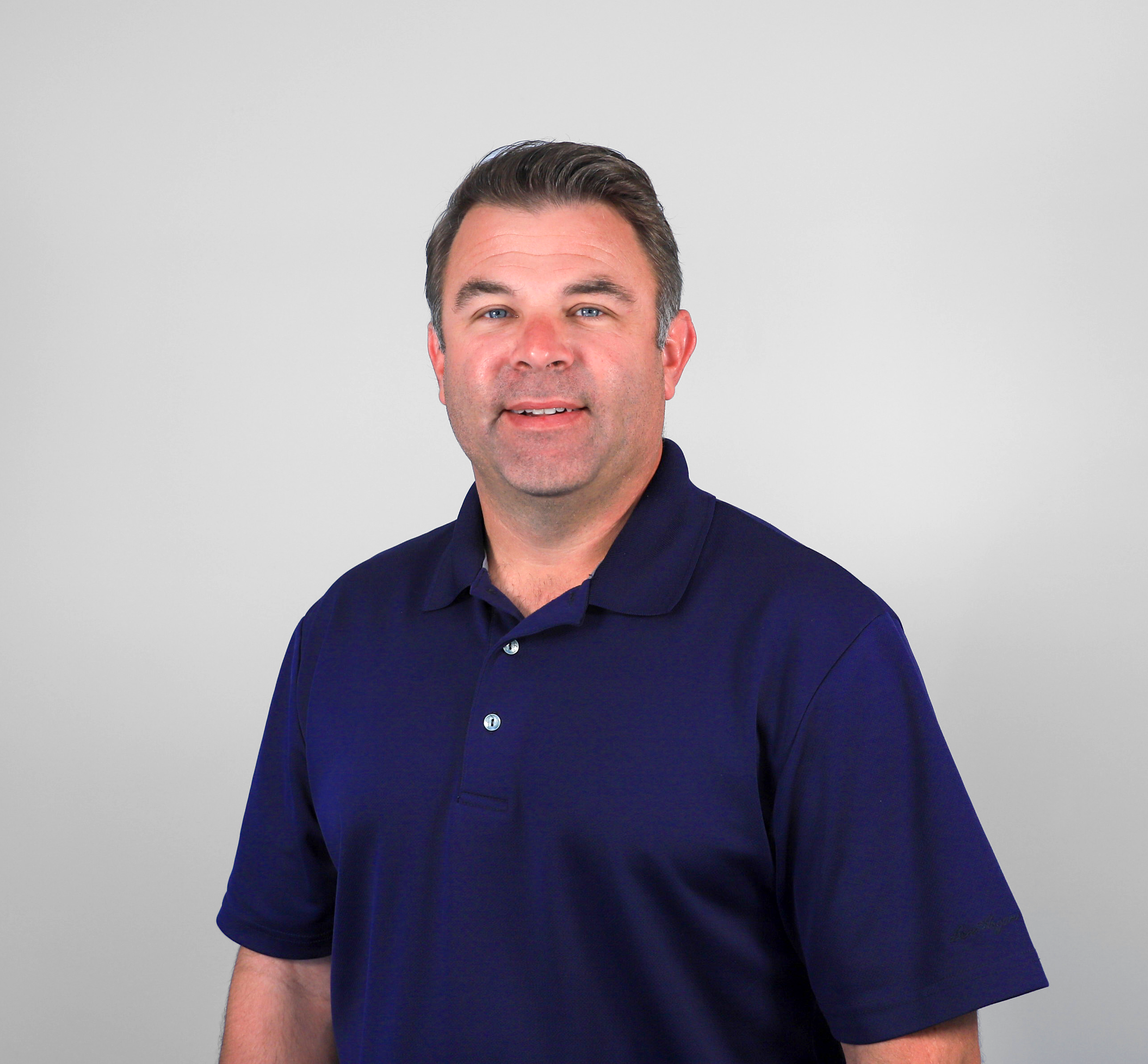 Man in navy polo shirt standing.