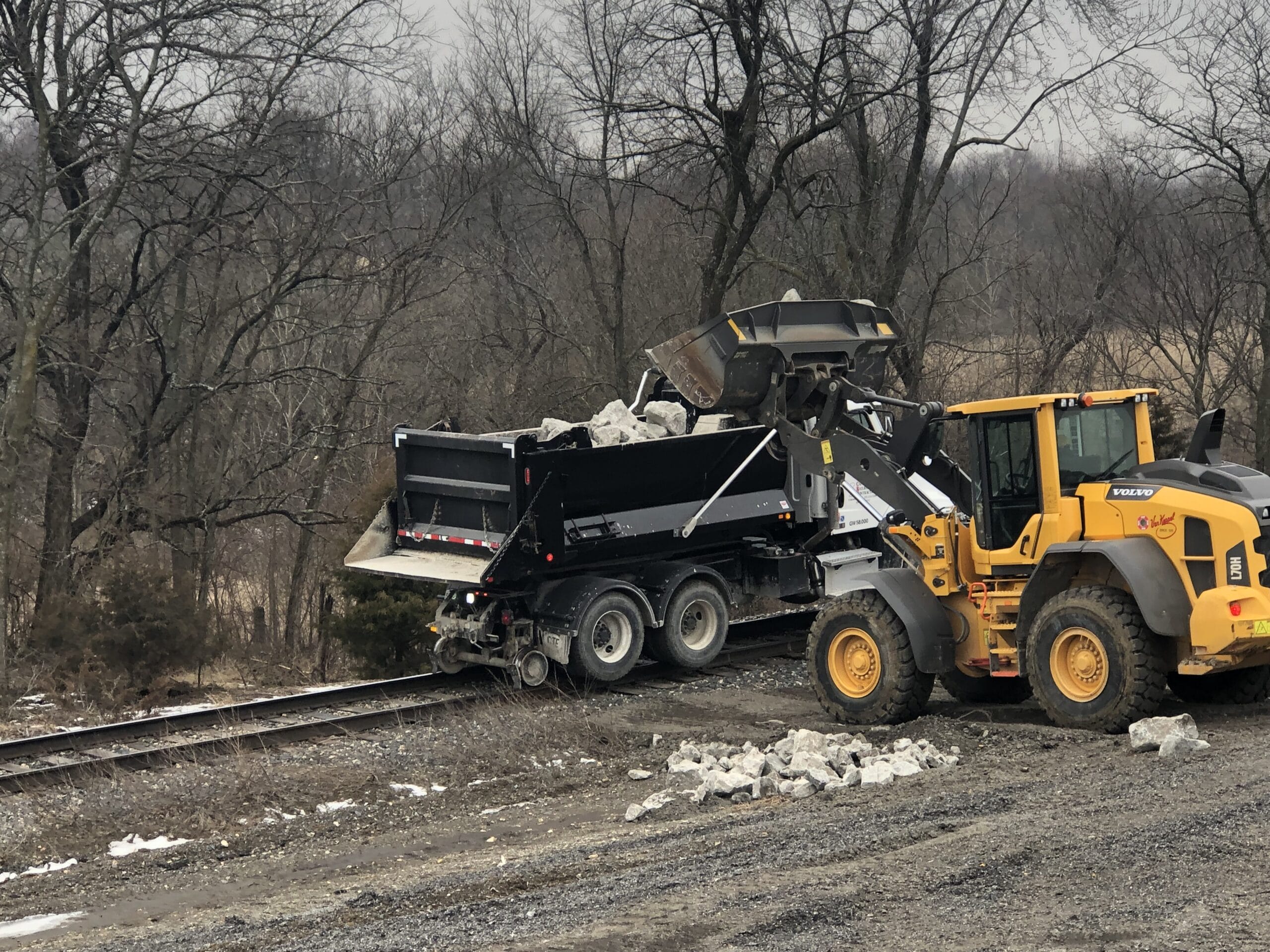 Dump truck unloading rocks near tracks