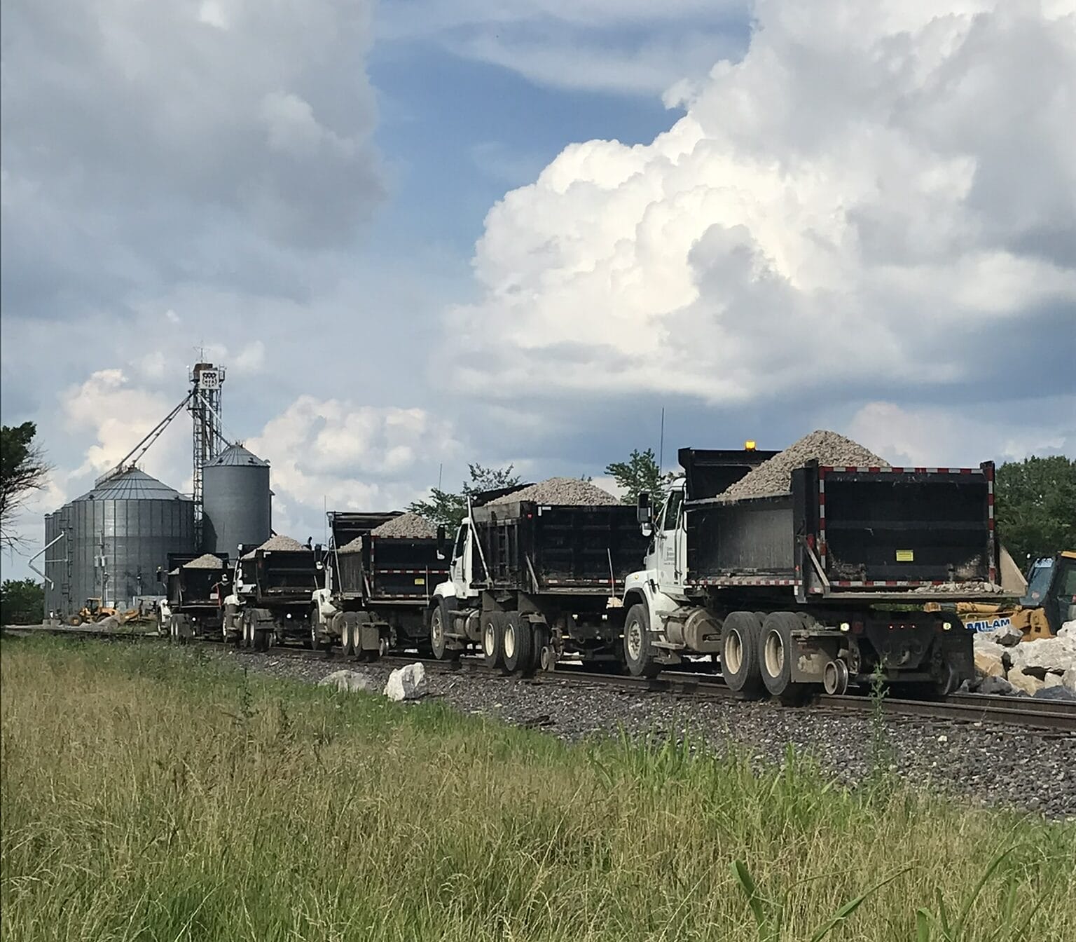 Trucks transporting gravel near silos