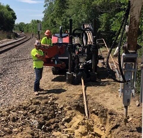 Workers operating drilling equipment near tracks