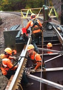 Workers repairing railway tracks outdoors.