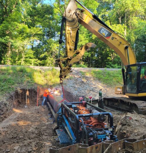 Excavator installing large underground pipe